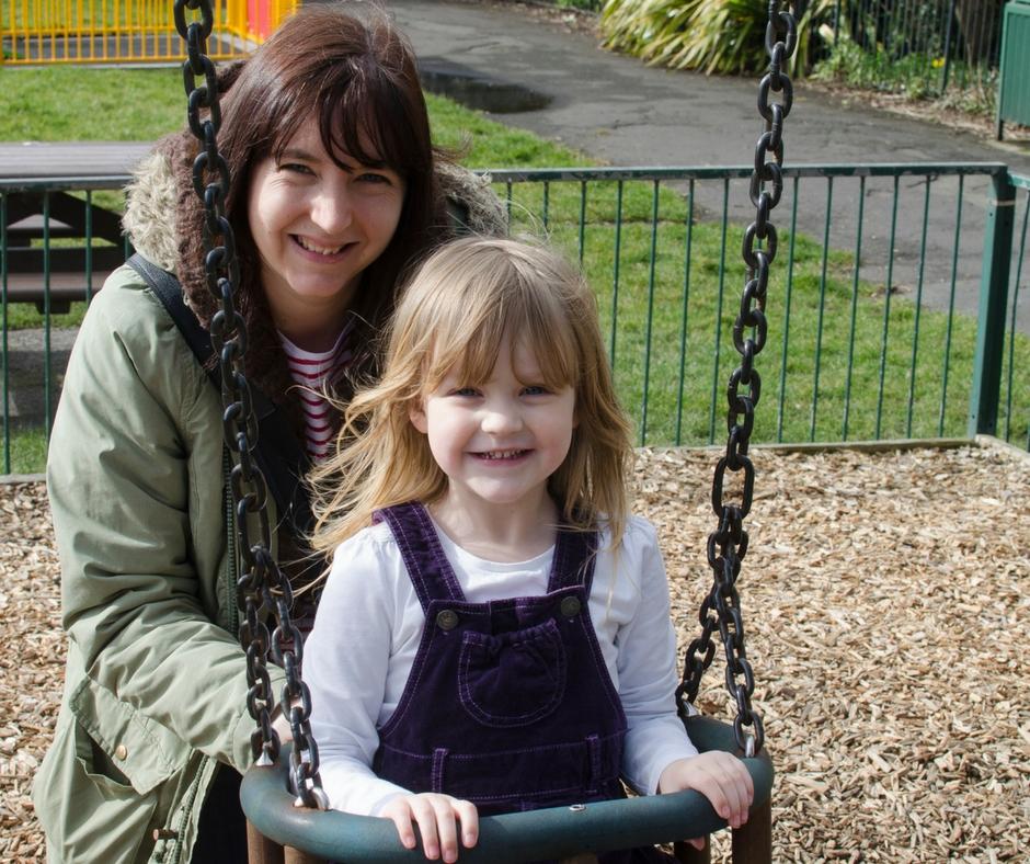 mother pushing daughter on swing