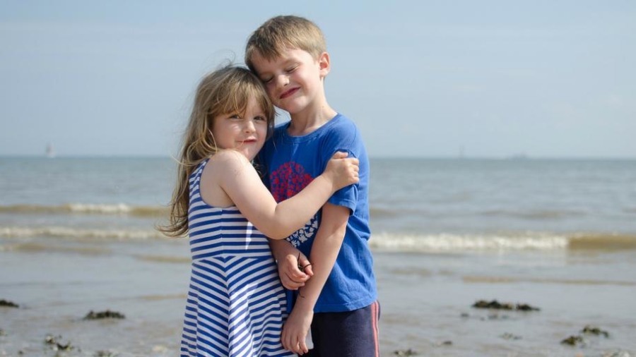 Siblings hugging on a beach